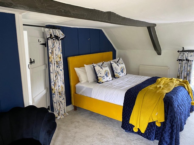 Cottage bedroom with navy walls and yellow accented fabric