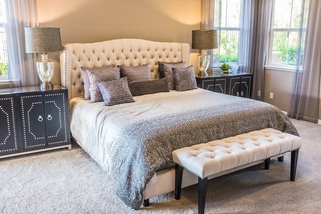 A grey toned bedroom with a plush headboard and matching cushions
